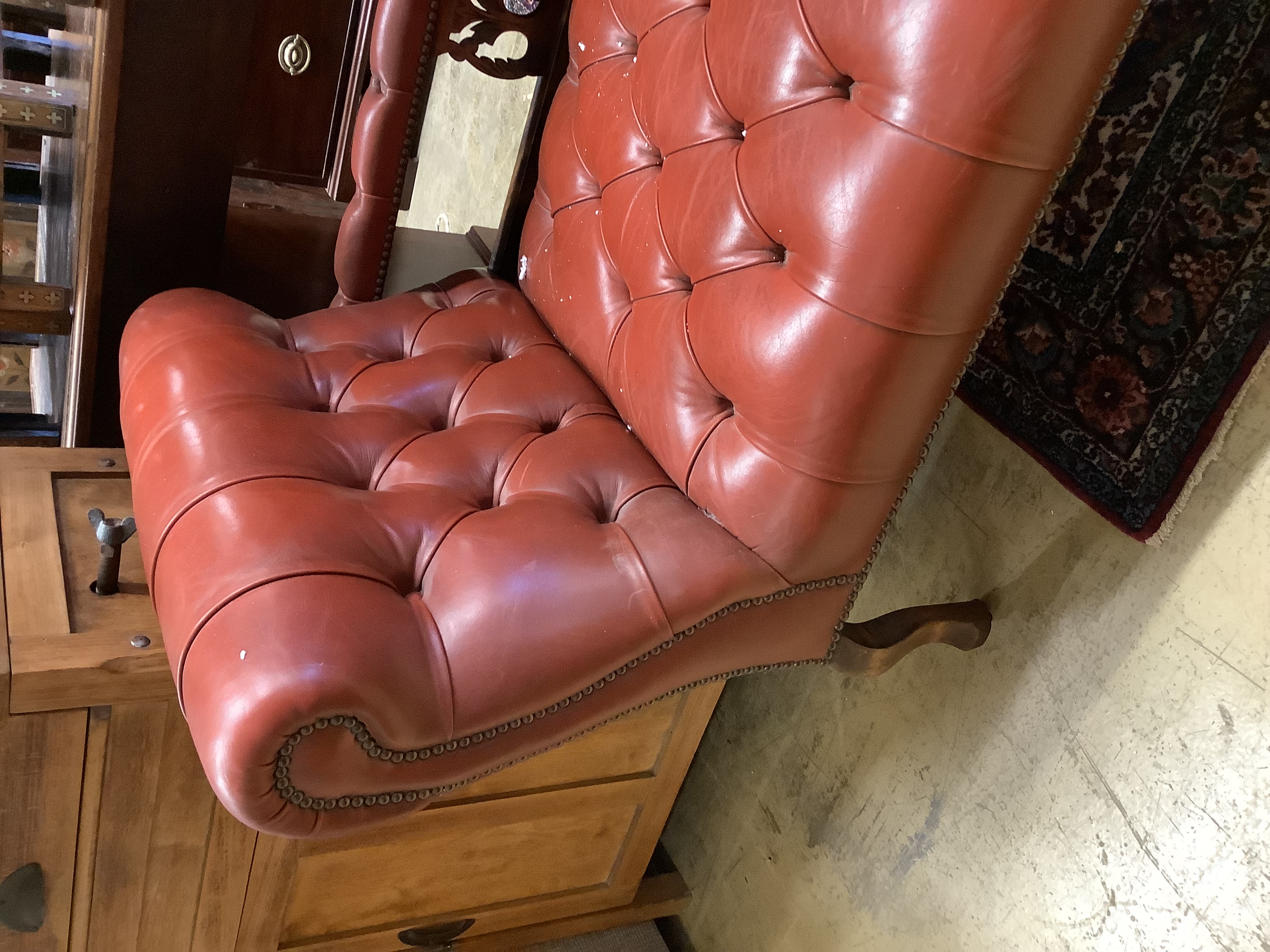 An Edwardian beech two-seater couch upholstered in buttoned burgundy hide on scrolled legs, length 160cm, depth 60cm, height 70cm